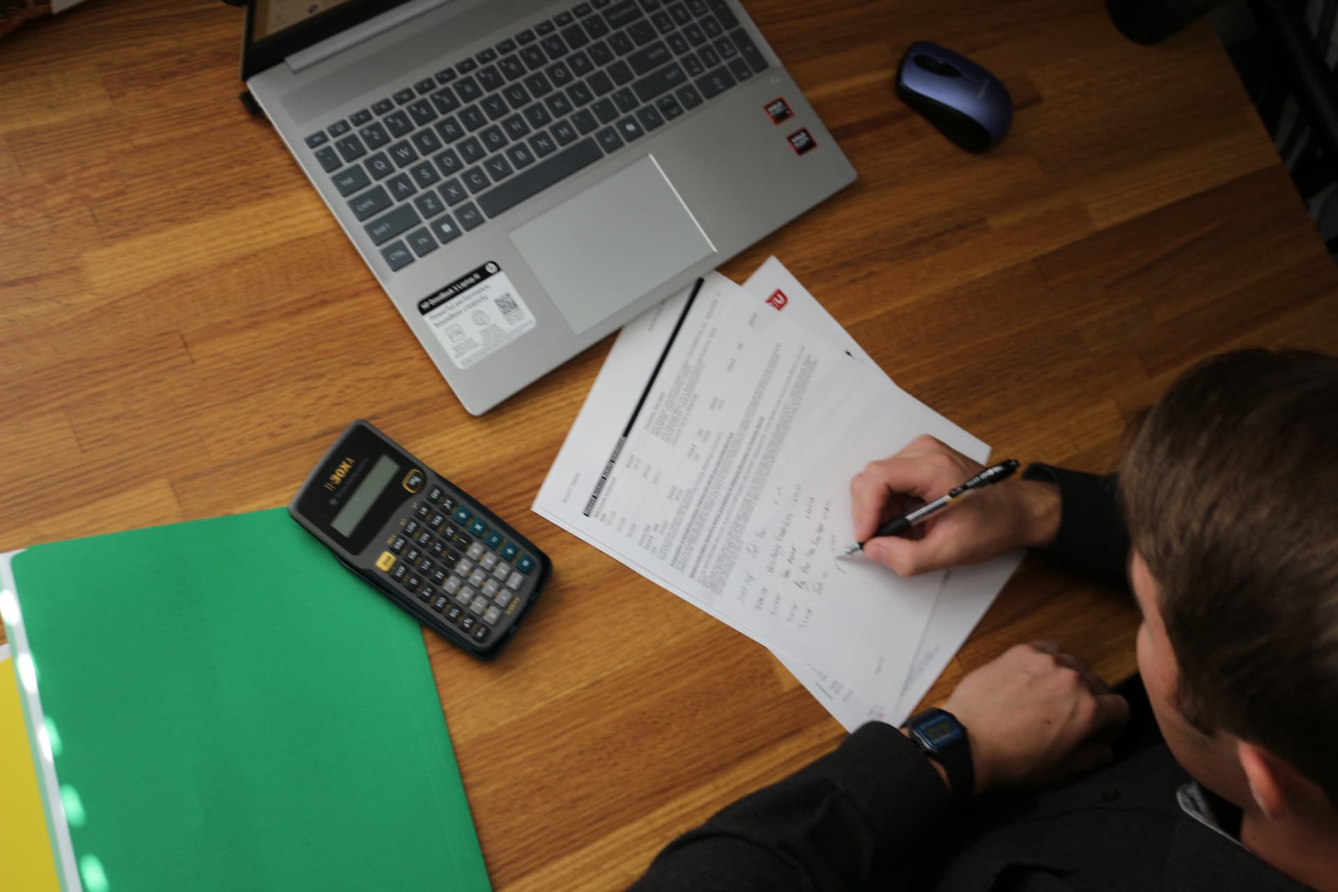 Reconciliation work in progress with statements, calculator and laptop